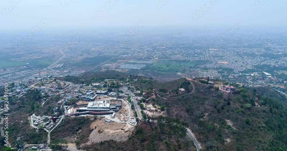 Aerial shot of hill covered in forest and village with temples on top of it Aerial shot of hill covered in forest and village with temples on top of it