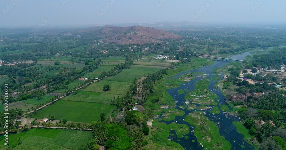 Aerial shot of river covered in algae, fields along and hill in background Aerial shot of river covered in algae, fields along and hill in background
