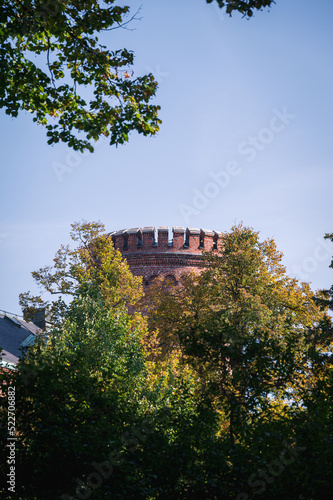 The round tower of Kungshuset is peeking up behind the autumn colored trees on a sunny fall day in Lund Sweden