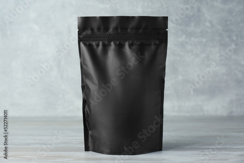 One blank foil package on wooden table against light grey background