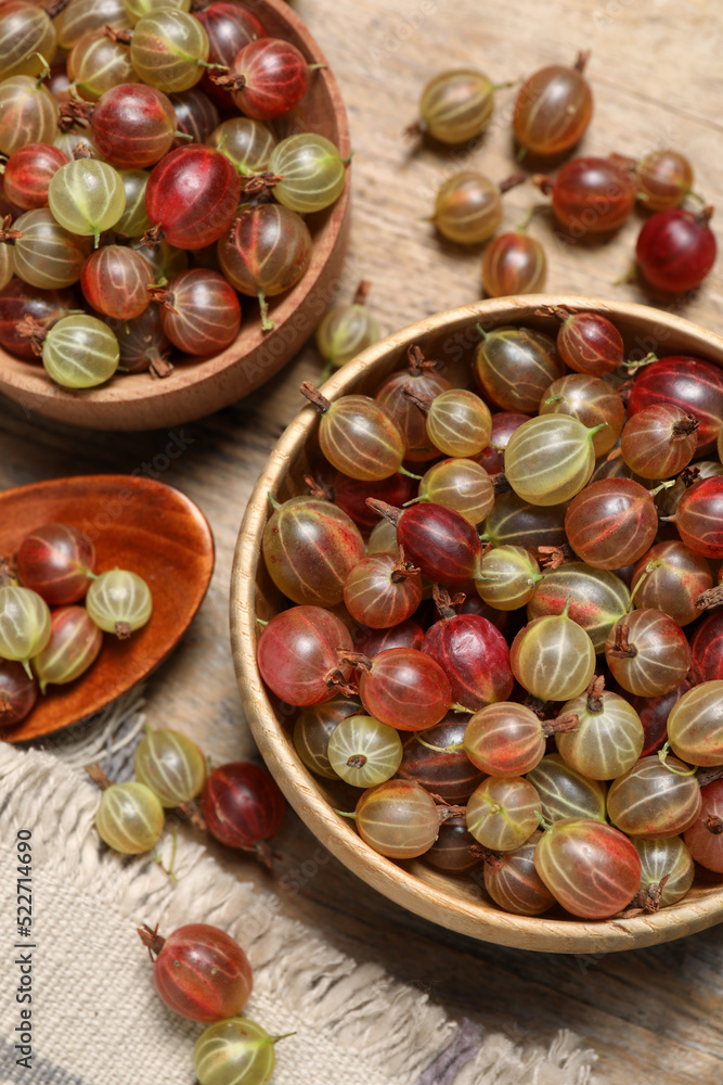 Many fresh ripe gooseberries on wooden table, flat lay