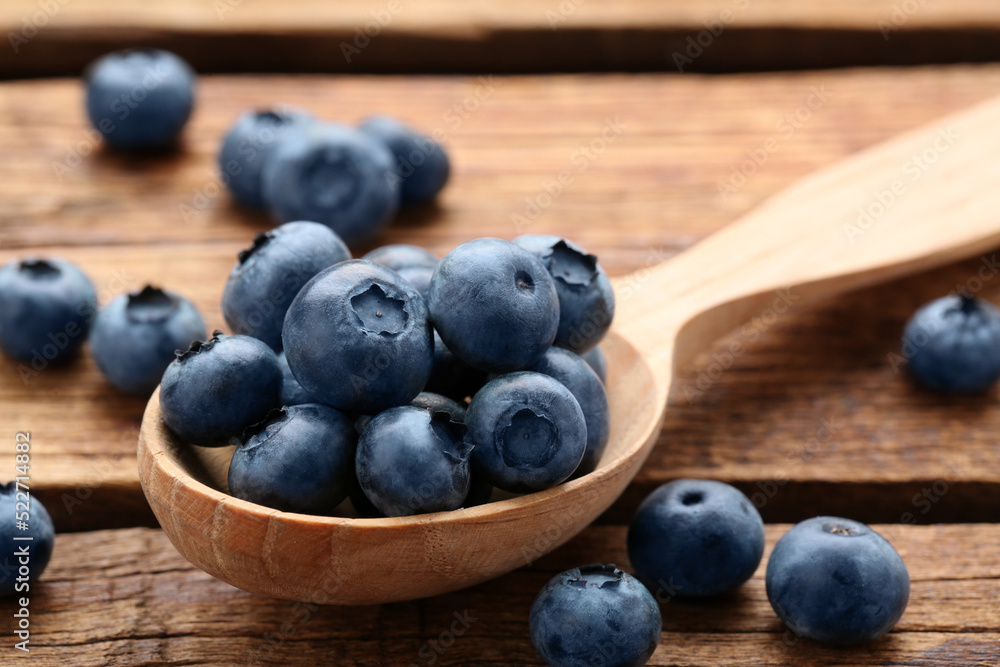 Spoon with tasty fresh blueberries on wooden table, closeup Spoon with tasty fresh blueberries on wooden table, closeup