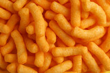 Tasty cheesy corn puffs as background, top view