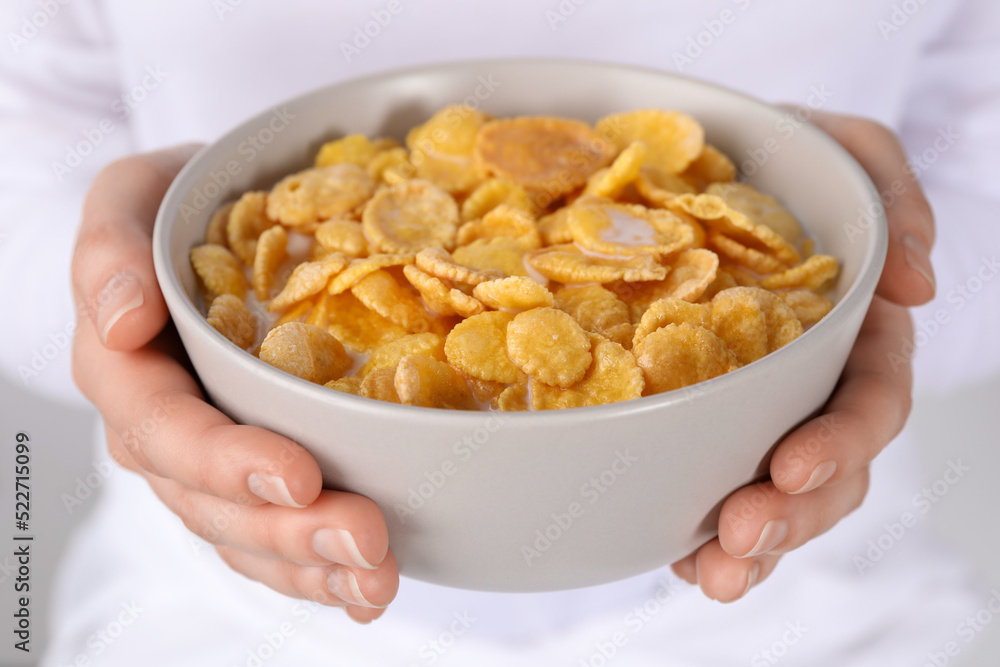 Woman holding bowl of crispy corn flakes with milk, closeup Woman holding bowl of crispy corn flakes with milk, closeup