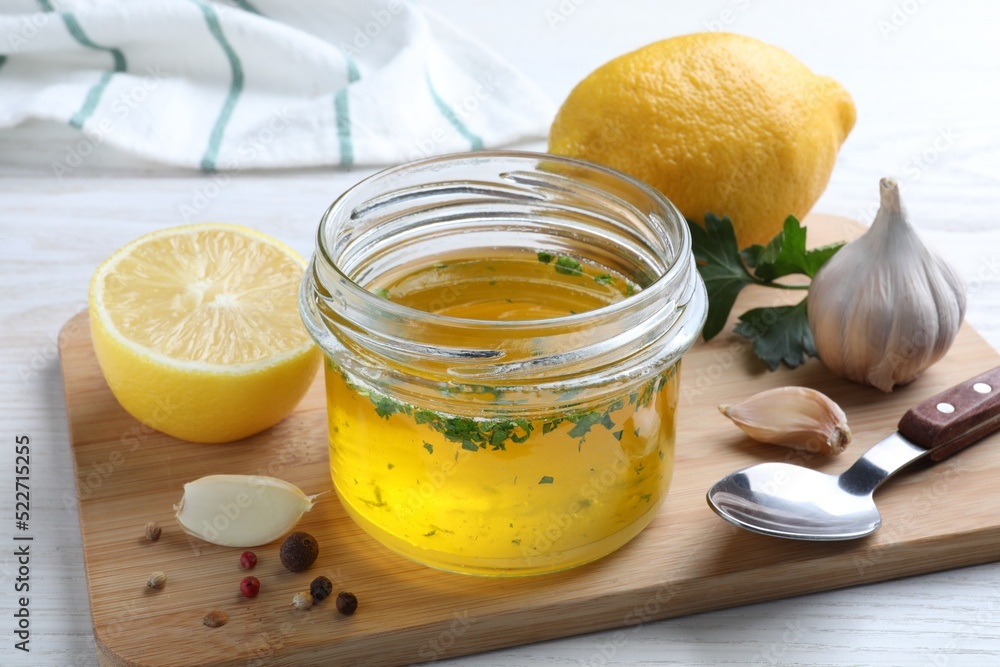 Jar with lemon sauce and ingredients on white wooden table. Delicious salad dressing Jar with lemon sauce and ingredients on white wooden table. Delicious salad dressing