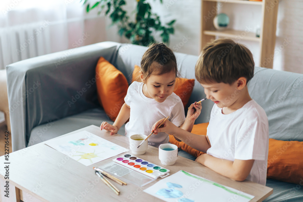 Children paint nature on sheets while sitting at the table. Children paint nature on sheets while sitting at the table.