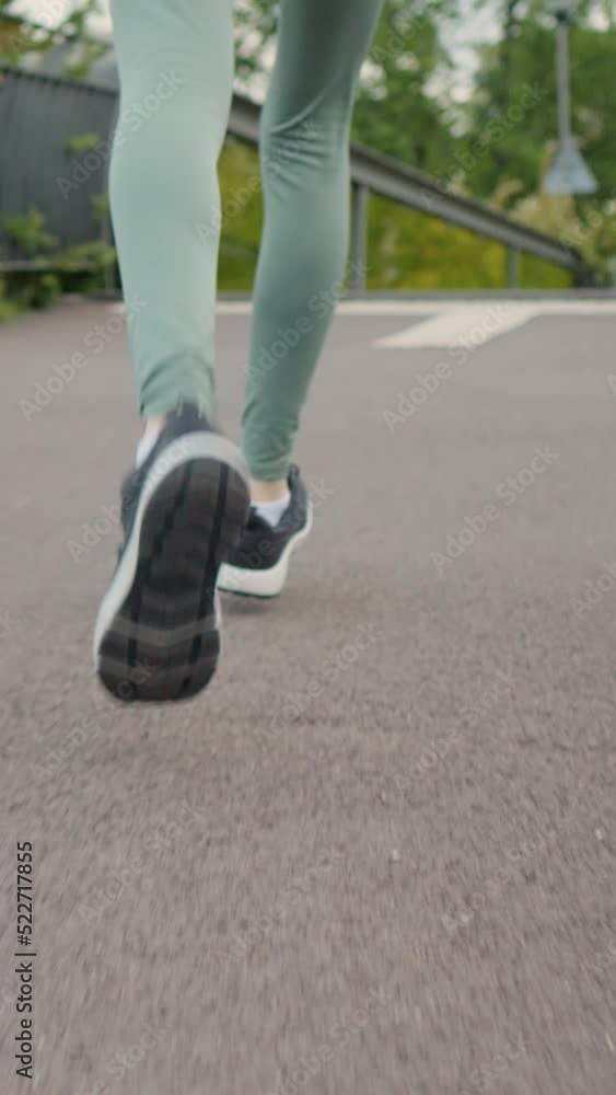 Vertical Screen: Woman practicing morning jog workout in the park early morning. Close-up slim female legs. Female runner legs jogging outdoor background. Vertical Screen: Woman practicing morning jog workout in the park early morning. Close-up slim female legs. Female runner legs jogging outdoor background.