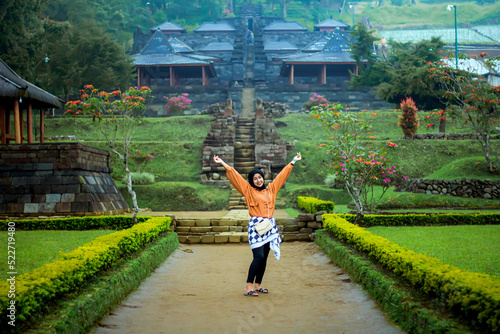 Asian woman in hijab is on vacation and visits the historical site of Candi Cetho in Tawangmangu, Karanganyar Regency, Central Java.