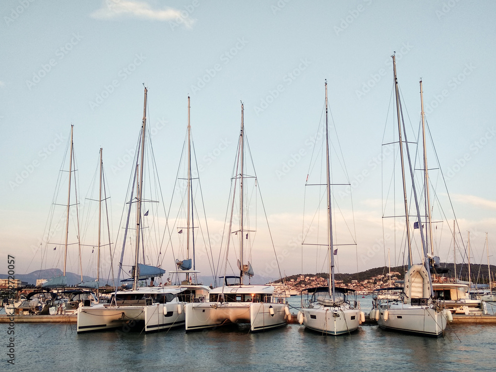 Sailing yachts stand in a row in the marina at sunset