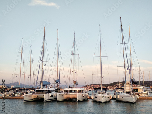Sailing yachts stand in a row in the marina at sunset © Kate