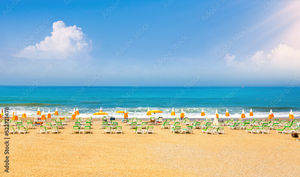 Beautiful image of Mediterranean golden beach with blue skies, white clouds, expanse of turquoise sea, sun loungers and umbrellas. Beautiful image of Mediterranean golden beach with blue skies, white clouds, expanse of turquoise sea, sun loungers and umbrellas.