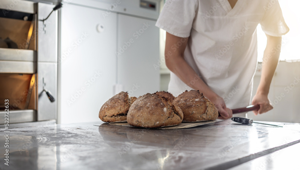 The baker is a man in the process of baking bread. Production of bakery products as a small business The baker is a man in the process of baking bread. Production of bakery products as a small business