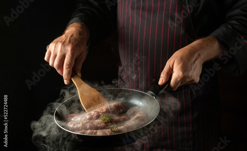 Canvas Print The chef is frying sausages for hot dogs in a frying pan