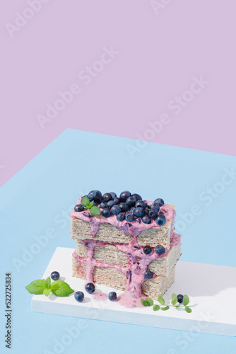 waffle cake with blueberries and mint on a blue and purple background. Hard light.