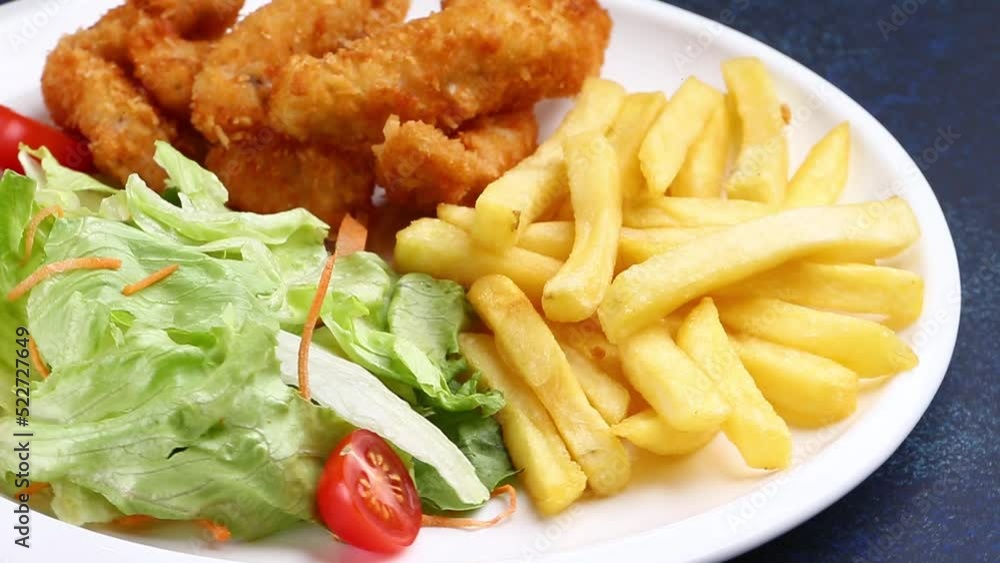 French fries, fried chicken and salad in a plate. Selective focus. French fries, fried chicken and salad in a plate. Selective focus.