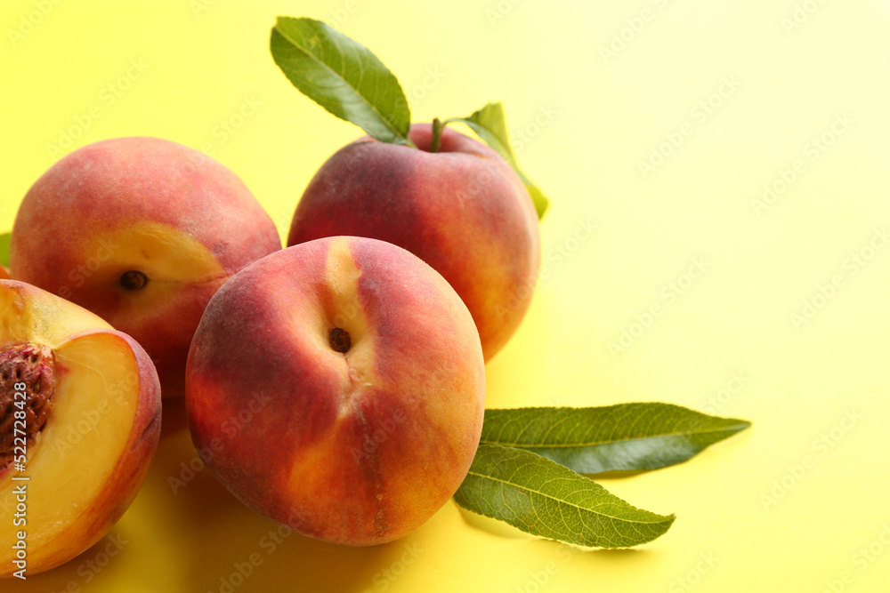 Fresh ripe peaches and green leaves on yellow background, closeup. Space for text Fresh ripe peaches and green leaves on yellow background, closeup. Space for text