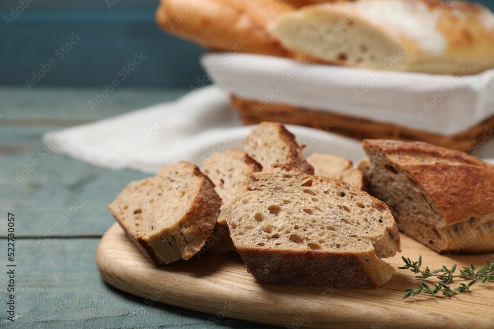 Cut buckwheat baguette with thyme on light blue wooden table, closeup Cut buckwheat baguette with thyme on light blue wooden table, closeup