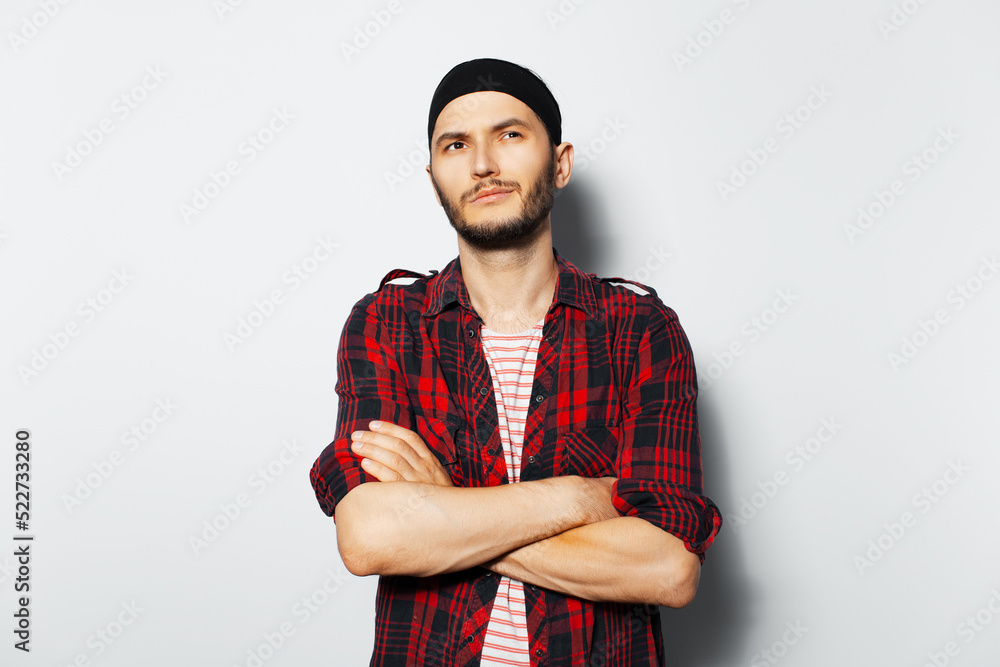Studio portrait of young handsome guy, with crossed arms. Wearing red plaid shirt and black headband. Studio portrait of young handsome guy, with crossed arms. Wearing red plaid shirt and black headband.