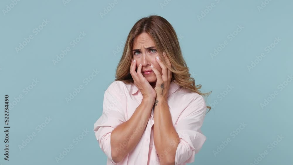 Young scared shocked woman 30s wear pink shirt white t-shirt look camera cover hiding face with hands peep through fingers isolated on plain pastel light blue cyan background People lifestyle concept Young scared shocked woman 30s wear pink shirt white t-shirt look camera cover hiding face with hands peep through fingers isolated on plain pastel light blue cyan background People lifestyle concept