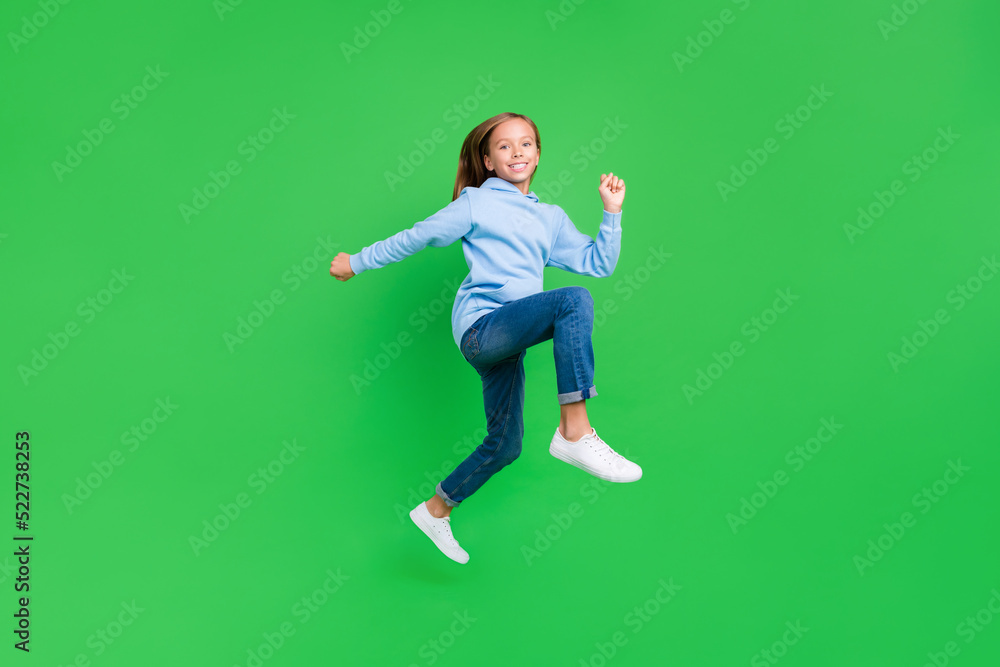Full size photo of active crazy little girl running fast hurrying be late wear stylish blue sweatshirt isolated on green color background Full size photo of active crazy little girl running fast hurrying be late wear stylish blue sweatshirt isolated on green color background