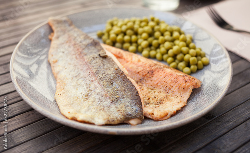 Appetizing baked trout fillets with green peas