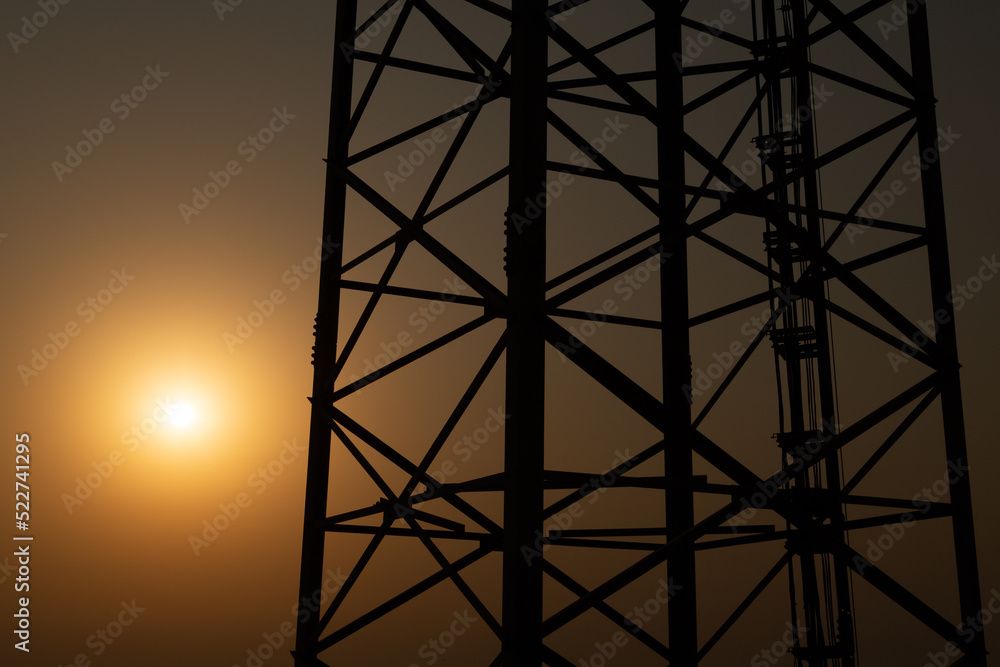 Antenna pole with over sunset sky. Summer abstract technology background. Beauty nature background with sun. Silhouettes of antenna pole.