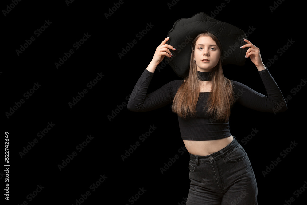 Young woman in black short top, jeans and wide-brimmed hat poses in the studio. Black background. Copy space, mockup Young woman in black short top, jeans and wide-brimmed hat poses in the studio. Black background. Copy space, mockup