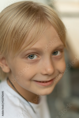 Close-up portrait of blond boy with blue eyes looking into the camera. Fair-haired child smiling.