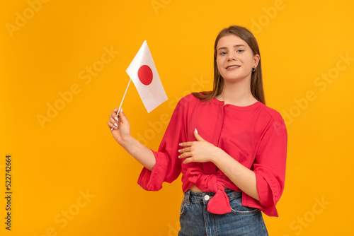 Teenage girl with the flag of Japan on orange background. Learn Japanese. Study and travel to Japan.