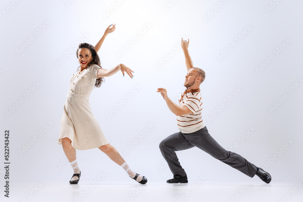 Excited young man and woman in retro style outfits dancing lindy hop isolated on white background. Timeless traditions, 60s ,70s american fashion style. Excited young man and woman in retro style outfits dancing lindy hop isolated on white background. Timeless traditions, 60s ,70s american fashion style.