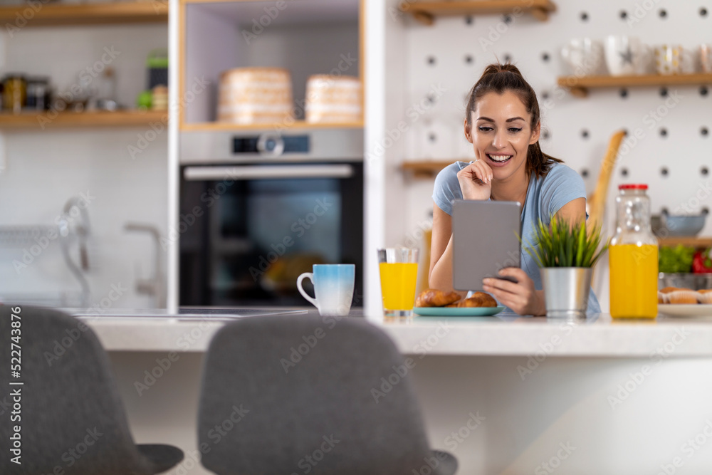 Woman using digital tablet while having breakfast Woman using digital tablet while having breakfast