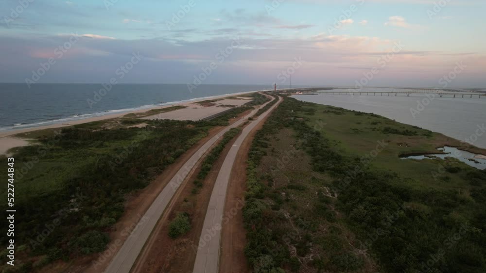 An aerial view of the Robert Moses Water Tower in the far distance, on the southern coast of Long Island, NY. The drone camera dolly in and pan right over the narrow land during a colorful sunrise. An aerial view of the Robert Moses Water Tower in the far distance, on the southern coast of Long Island, NY. The drone camera dolly in and pan right over the narrow land during a colorful sunrise.