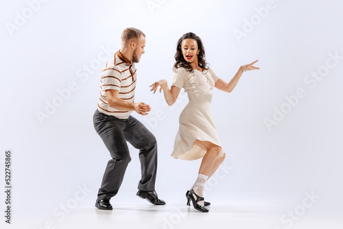 Excited young man and woman in retro style outfits dancing lindy hop isolated on white background. Timeless traditions, 60s ,70s american fashion style. photo