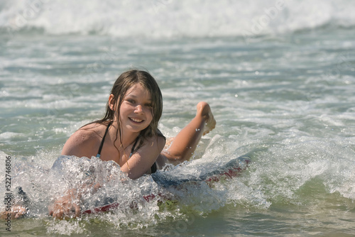 Cute portrait of a girl bodyboarding in the waves in summer