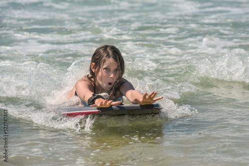 Cute portrait of a girl bodyboarding in the waves in summer © Image'in