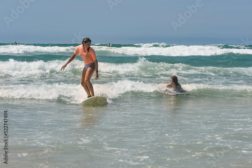 Two sisters surfing together in the waves in summer © Image'in