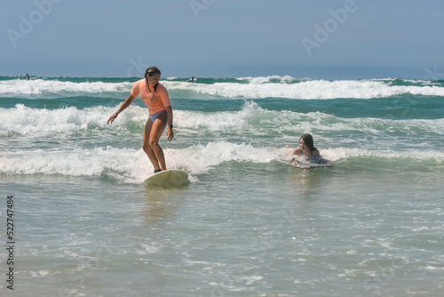 Quadro su tela Two sisters surfing together in the waves in summer