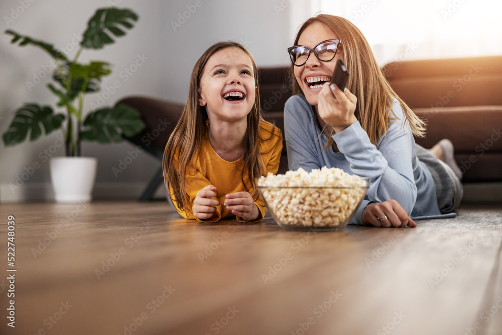 Cute little girl watching TV with her mom Stock Photo | Adobe Stock