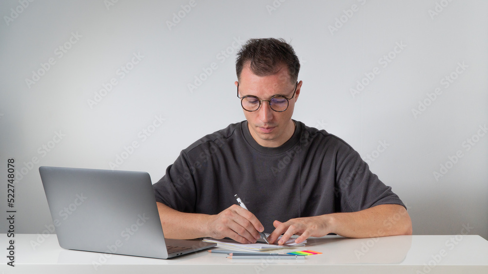 A student with glasses learns with a laptop and notebooks A student with glasses learns with a laptop and notebooks