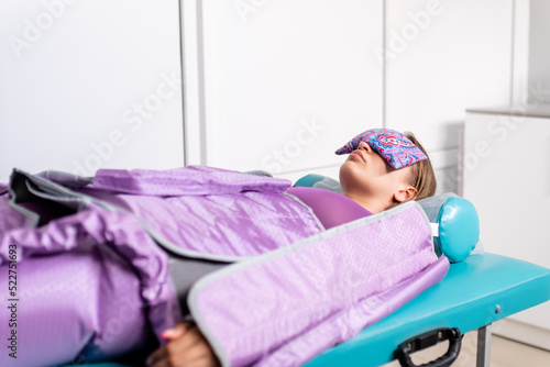 Photos Woman lying with closed eyes during pressotherapy session in beauty clinic