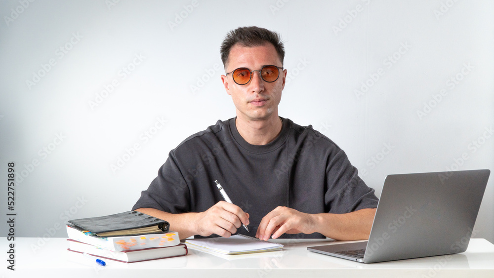 A student with glasses writes in a notebook - education and work A student with glasses writes in a notebook - education and work