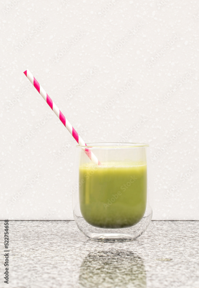 Matcha tea in a glass cup with a red straw stands on a steel Matcha tea in a glass cup with a red straw stands on a steel