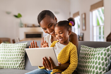 Cute little daughter and african mother using digital tablet to do a video call
