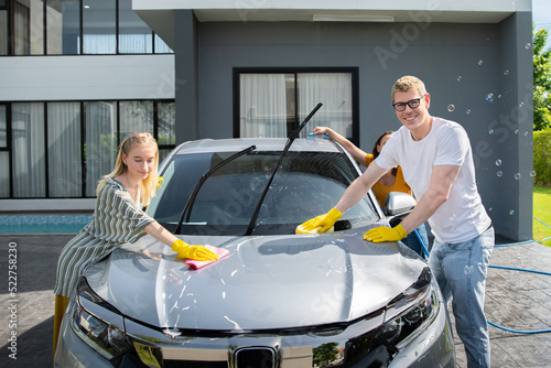 happy family wash and clean an automative car at home garage with water jet and shampoo wax  on weekend photo