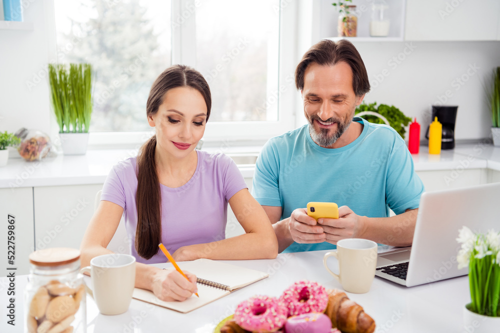 Photo of cute cheerful age boyfriend girlfriend wear t-shirts typing modern gadget writing breakfast recipe indoors room home