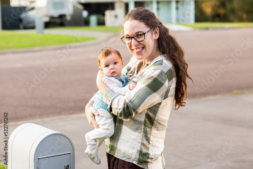 Mum with young baby checking the mailbox smiling together outside