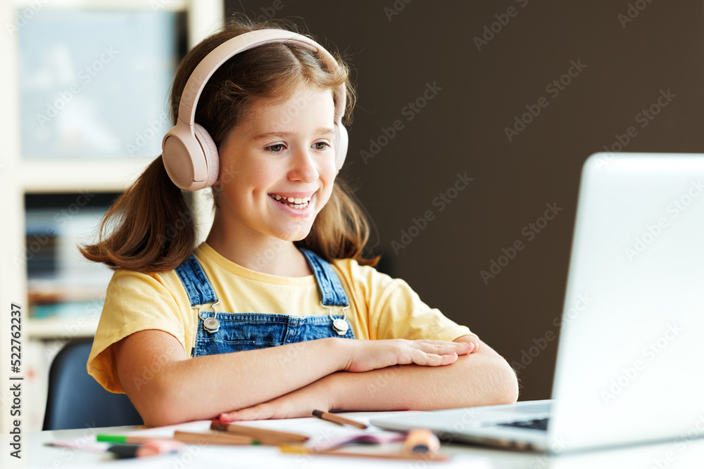 Cheerful girl looking at laptop screen during online lesson Cheerful girl looking at laptop screen during online lesson