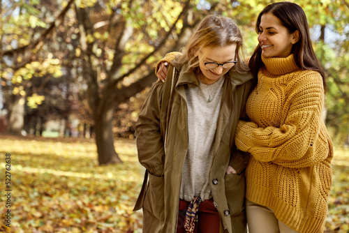 Senior woman with her adult daughter walking at the park during the autumn