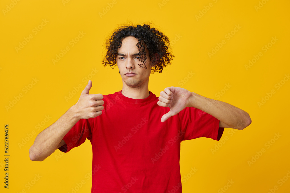 Dissatisfied funny Caucasian young man in red t-shirt show Dis Like gesture posing isolated on yellow studio background. The best offer with free place for advertising. Emotions for everyday concept Dissatisfied funny Caucasian young man in red t-shirt show Dis Like gesture posing isolated on yellow studio background. The best offer with free place for advertising. Emotions for everyday concept