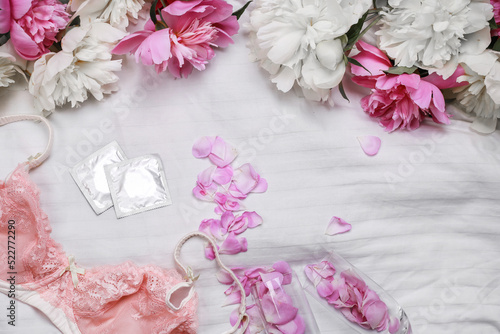 omen's lace lingerie on a white bed. Tulips, perfume, lipstick, condoms. Woman devices. Date. Romantic day. Flat lay with copy space